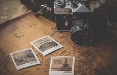 Une caméra photo et trois polaroids sont installés sur une carte du monde jaunis.