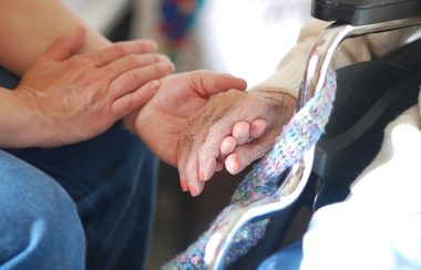 a close up of two people, one of them elderly, holding hands