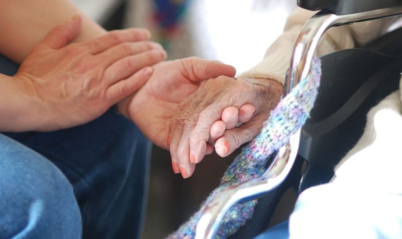 a close up of two people, one of them elderly, holding hands