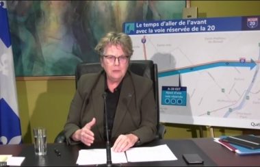 Chantal Rouleau se retrouve dans son bureau en conférence zoom. À sa droite, un drapeau du Québec et à sa gauche un plan montrant la nouvelle voie réservée sur l'Autoroute 20.
