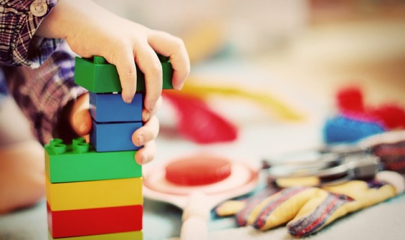 Des petites mains d'enfants jouent avec des blocs de couleurs.