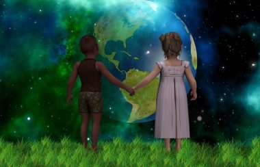 Deux enfants debout sur l'herbe se tiennent la main devant un fond de planète terre dans l'univers.