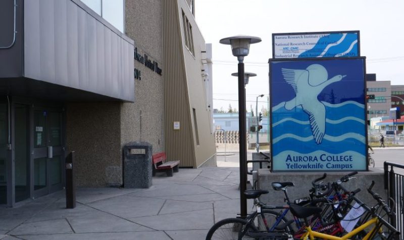 Des vélos sont stationnés devant l'affiche du Campus du Yellowknife du Collège Aurora, à l'entrée de l'établissement.