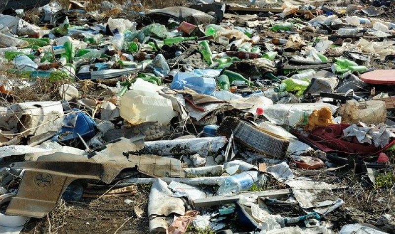 Décharge résiduelle avec plusieurs détritus comme des bouteilles de vitres et de plastiques et du carton.