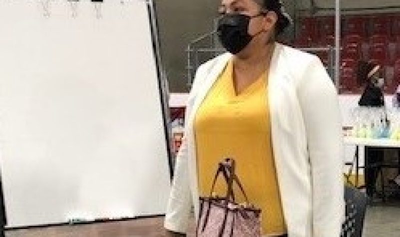 First Nations lady wearing white and yellow shirt with mask talking about treaties and culture