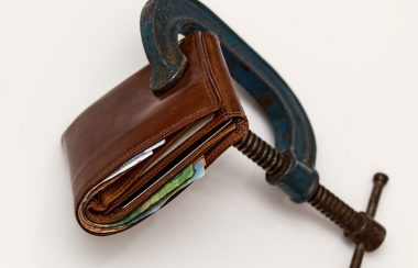 A blue and black metal clamp squeezes a brown leather wallet