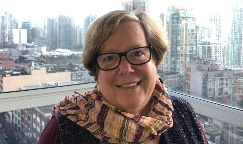 A headshot of Libby Davies against a window looking out over Vancouver.