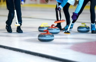 Sur une patinoire des personnes jouent au curling.