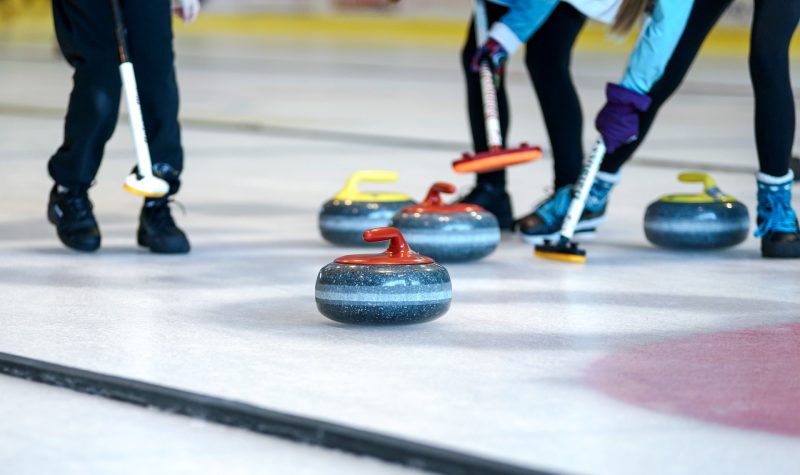 Sur une patinoire des personnes jouent au curling.