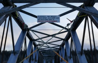 a photo of the Quic Bridge with a sign that says no respect, only neglect, I need repair, MOTI don't care, not much since 1991