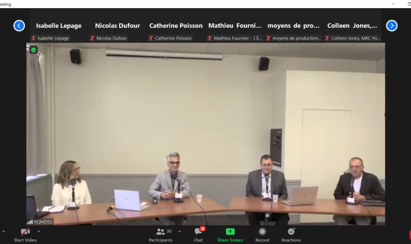 A screenshot of a zoom meeting showing four people sitting at a table.