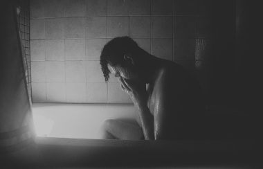 Un homme pleure dans un bain. La photo est en noir et blanc