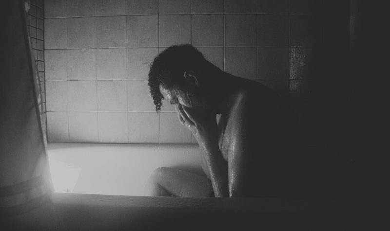Un homme pleure dans un bain. La photo est en noir et blanc