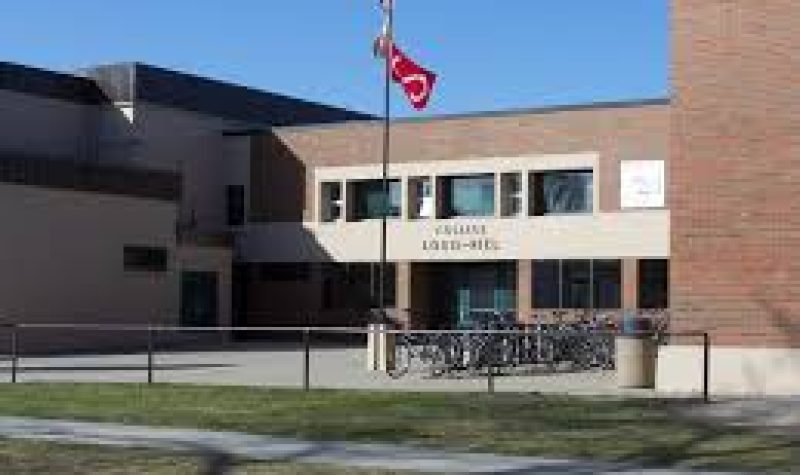 Le devant de l'école avec le drapeau métis et franco-manitobain flotte dans le vent.