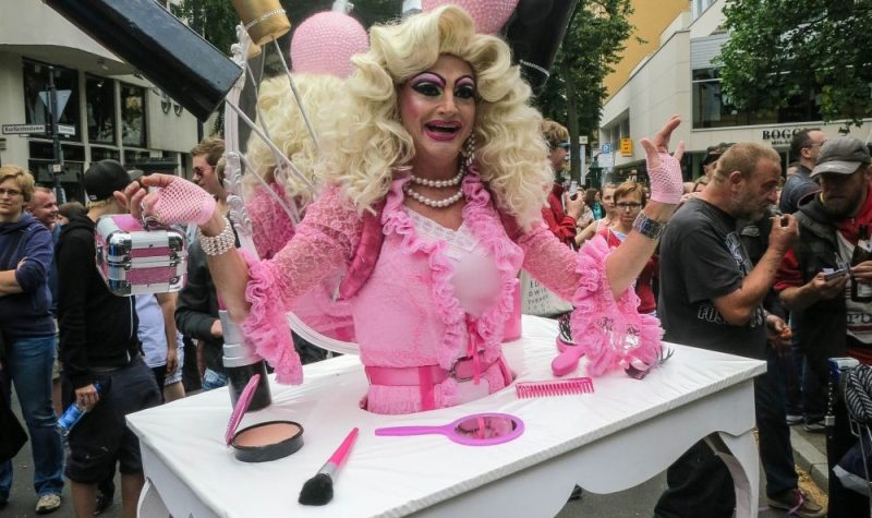 Une drag queen habillée en costume rose dans un lieu public