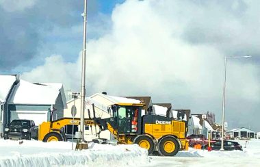 Une déneigeuse jaune déblaie le coin d'une rue