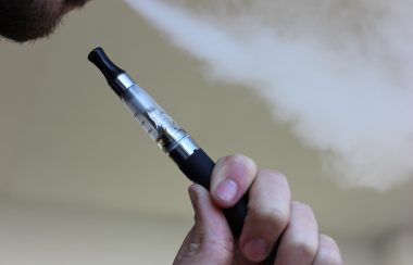 A black and white vape pen being smoked by a man.