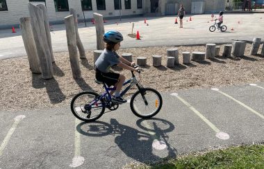 Un petit garçon qui fait du vélo et qui porte un casque.