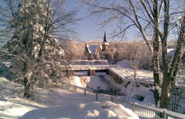 Image of the church downtown Knowlton during the winter. The photo is taken between trees from a distance.