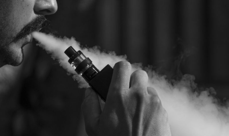 un homme souffle de la fumée après avoir fumé une cigarette électronique