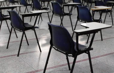 A photo of empty desks are shown in a classroom.