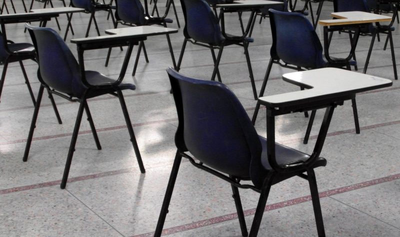 A photo of empty desks are shown in a classroom.
