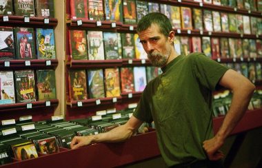 A man standing in front of shelves of movies