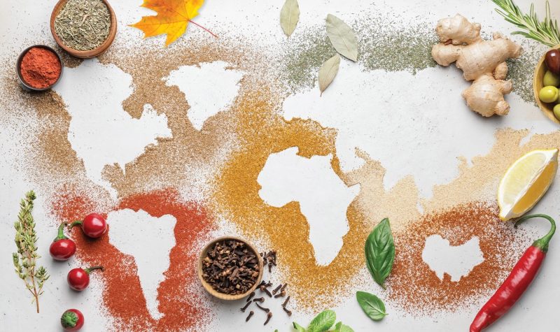 La carte du monde réalisée avec des épices, les couleurs sont chaudes et des légumes sont disposé un peu partout autour des épices