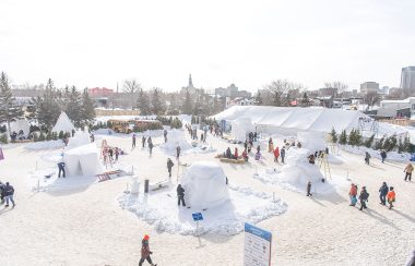 Le parc du voyageur en hiver, une vue élvée, des personnes circulent entre des sculptures de neige.