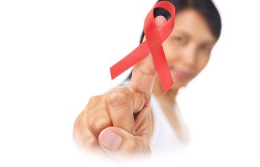A person holding up a red ribbon, symbolizing HIV