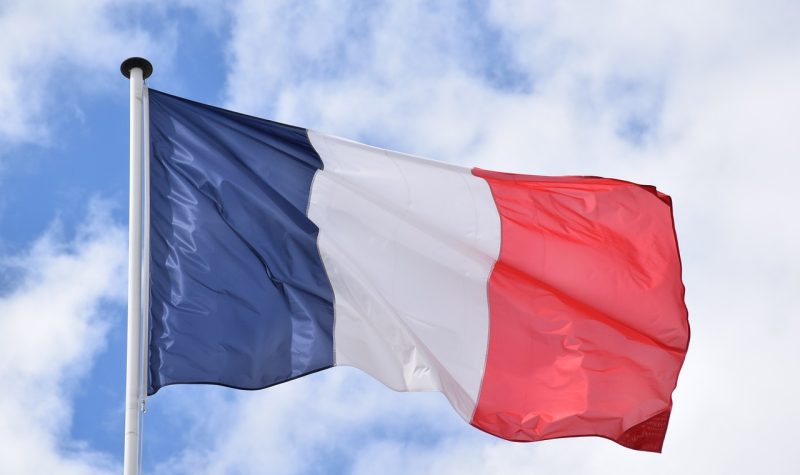 Le drapeau de la France avec le ciel nuageux en arrière plan.