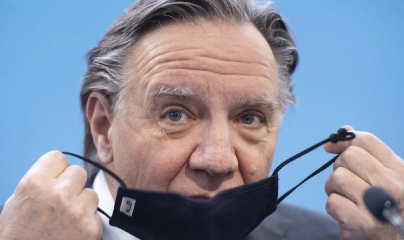 Picture of Premier Legault putting on a face mask.