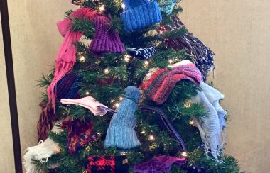 Un sapin décoré avec des mitaines et des tuques