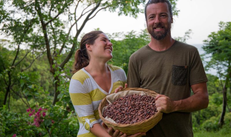 A man and a woman hold a basket of roasted cocoa.