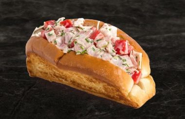 Un pain hot-dog avec des morceaux de jambons avec de la mayonnaise