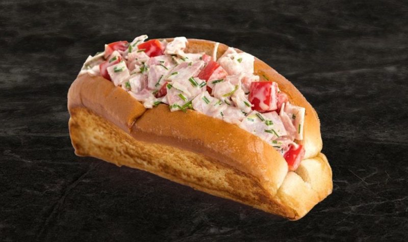 Un pain hot-dog avec des morceaux de jambons avec de la mayonnaise