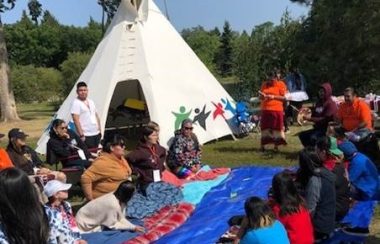 Youth sit on blankets getting ready to play hand games