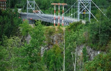 a large suspension bridge sits atop aspen and spruce trees across the Bulkley River in Northern BC.