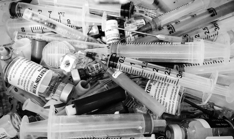 A black and white photo of a pile of syringes.