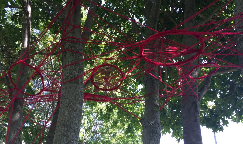 Art installation made of yarn hanging from trees