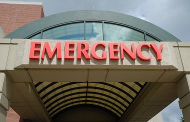 Entrée d'urgence d'une hôpital. Le mot Emergency est inscrit en rouge au-dessus de l'entrée.