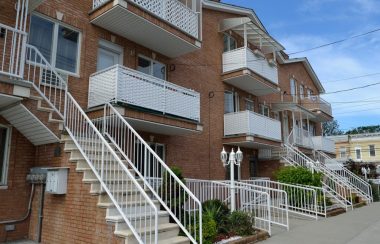 Plusieurs blocs d'appartements gris avec des escaliers et des balcons de couleur blanc