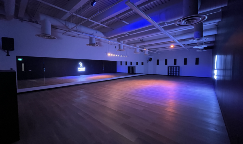 la salle de danse dans la pénombre avec le logo du studio brillant au mur