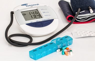 Une machine à prendre l'hypertension et des médicaments sont posés sur une table.