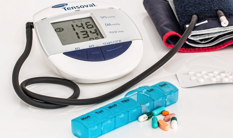 Une machine à prendre l'hypertension et des médicaments sont posés sur une table.