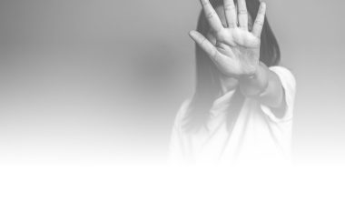 En noir et blanc, une femme fait un signe d'arrêt avec sa main