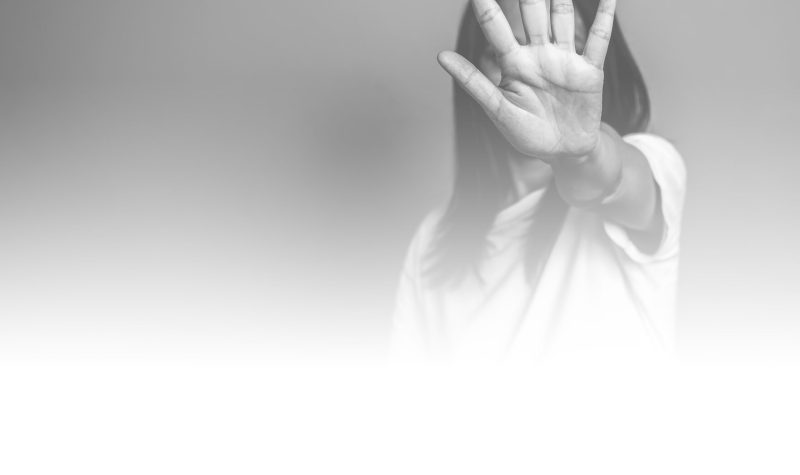 En noir et blanc, une femme fait un signe d'arrêt avec sa main