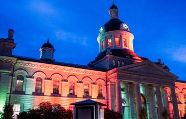 City Hall in Kingston, Ontario, illuminated with green light at night.