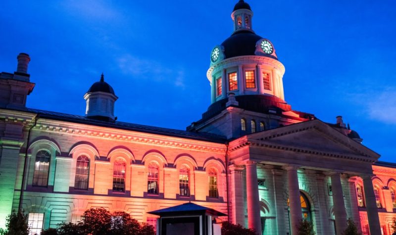 City Hall in Kingston, Ontario, illuminated with green light at night.
