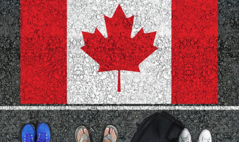 Un drapeau canadien dessiné au sol avec trois paires de pieds, en sandales et deux paires de baskets